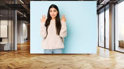 Young indian woman isolated on blue background showing number ten with hands. Wall mural