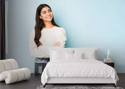 Young indian woman isolated on blue background smiling confident with crossed arms. Wall mural