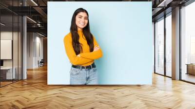 Young indian woman isolated on blue background who feels confident, crossing arms with determination. Wall mural