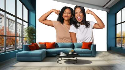 Young Latin friends in studio showing strength gesture with arms, symbol of feminine power Wall mural