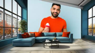 Young latin man holding an ice cream isolated happy, smiling and cheerful. Wall mural