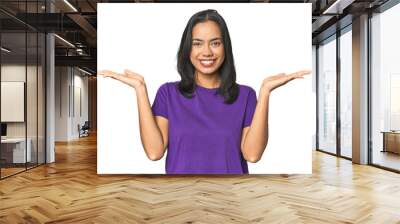 Young Latina posing in studio makes scale with arms, feels happy and confident. Wall mural