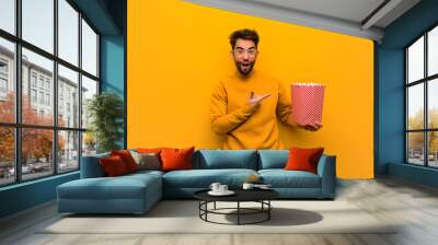 Young man holding popcorns holding something with hand Wall mural