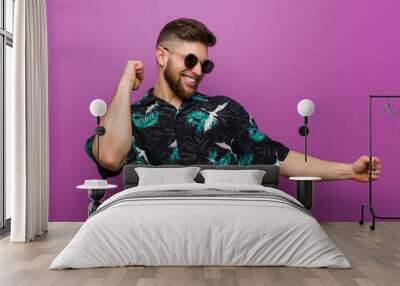 Young man wearing a vacation look dancing and having fun. Wall mural