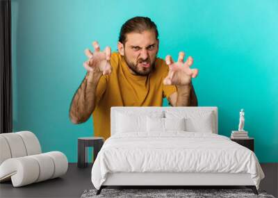 Young man with long hair look showing claws imitating a cat, aggressive gesture. Wall mural