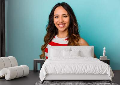 Young mexican woman isolated on blue background happy, smiling and cheerful. Wall mural