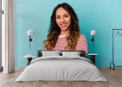 Young mexican woman isolated on blue background who feels confident, crossing arms with determination. Wall mural