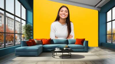 Young pretty arab woman against a yellow background laughing and having fun. Wall mural