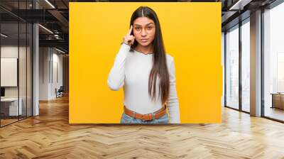 Young pretty arab woman against a yellow background pointing temple with finger, thinking, focused on a task. Wall mural