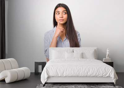 Young pretty arab woman looking sideways with doubtful and skeptical expression. Wall mural