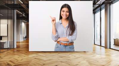 young pretty arab woman smiling cheerfully pointing with forefinger away. Wall mural