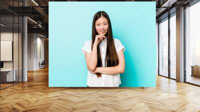 Young pretty chinese woman smiling happy and confident, touching chin with hand. Wall mural