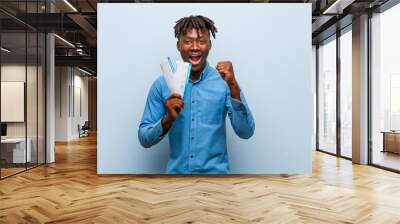 Young rasta black man holding an air tickets cheering carefree and excited. Victory concept. Wall mural