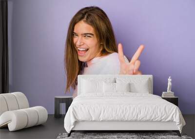 Young skinny caucasian girl teenager on purple background showing number two with fingers. Wall mural