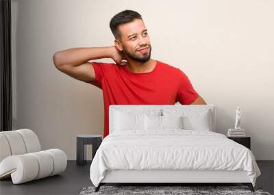 Young south-asian man touching back of head, thinking and making a choice. Wall mural