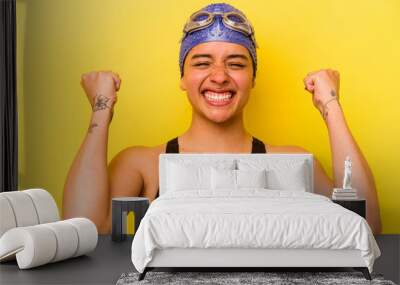 Young swimmer hispanic woman isolated on yellow background Wall mural