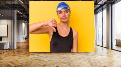 Young swimmer venezuelan woman isolated on yellow background showing a dislike gesture, thumbs down. Disagreement concept. Wall mural