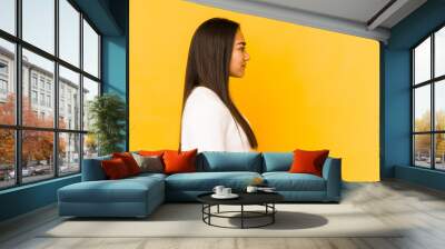 Young woman isolated on a yellow background gazing left, sideways pose. Wall mural