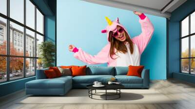 Young woman wearing an unicorn costume with sunglasses isolated Wall mural