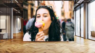 Happy young beautiful woman eating a big ice cream in the street Wall mural