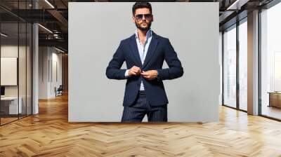 Elegant young handsome man in suite wearing glasses. Studio fashion portrait. Wall mural