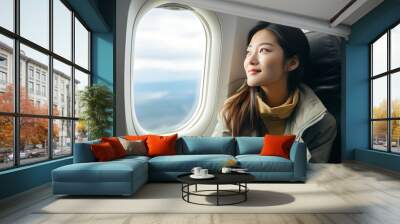 Asian young woman traveler sitting near windows and looking out the window on airplane during flight. Alone travelling concept Wall mural