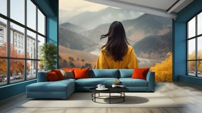 Back view woman wearing yellow coat enjoying the Autumn mountain view, woman in yellow jacket on nature autumn background Wall mural