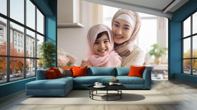 Portrait of happy muslim woman in hijab and her daughter hugging and smiling, mom and daughter love each other Wall mural