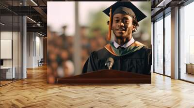 Portrait of young man graduate in a gown and a mortarboard stands at a podium and gives a graduation speech Wall mural