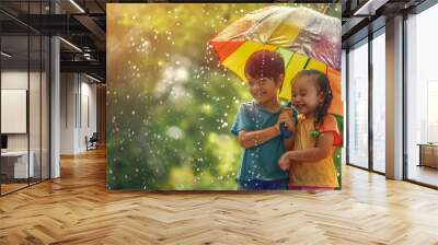 Smiling children under a colorful umbrella, enjoying the rain, expressing joy and friendship in a lush green setting Wall mural