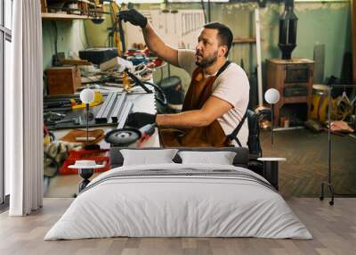 A bearded entrepreneur in a wheelchair works in his workshop. Wall mural