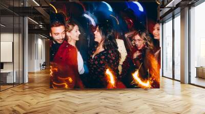 Group of friends having fun and holding sparklers at New Year's party Wall mural