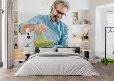 Senior man preparing smoothie in kitchen Wall mural