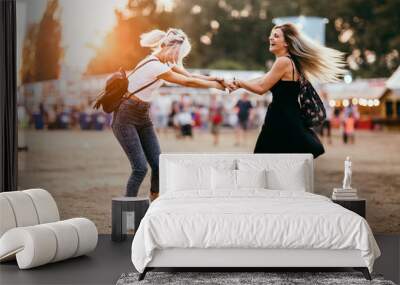 Two female friends spinning around and having fun at music festival Wall mural