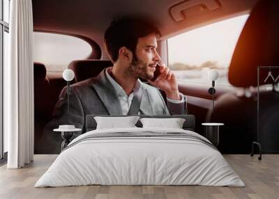 Young man sitting in the car and talking on a phone Wall mural