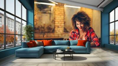 young woman at cafe drinking coffee and using mobile phone Wall mural