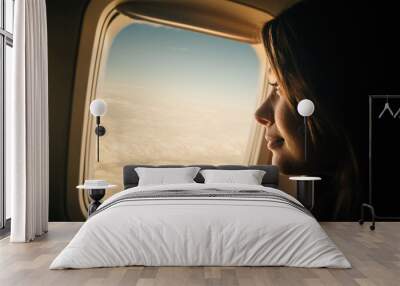 Young woman looking through window in airplane Wall mural