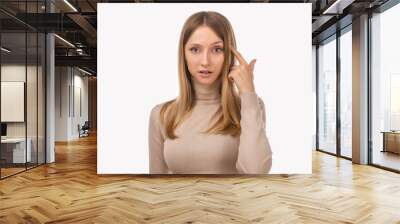 Photo of thinking young woman pointing with finger at head. Be smart and think. Studio shot, white background Wall mural