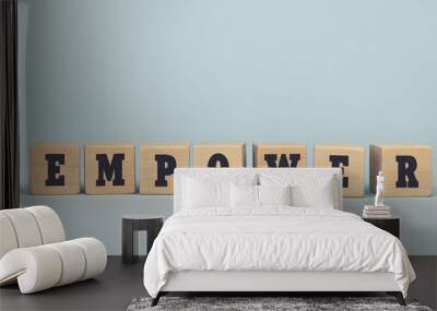 The word EMPOWER made from wooden cubes on blue background Wall mural