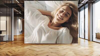 smiling woman wakes up comfortably in the morning and lies down sleep on white bed relaxing Wall mural