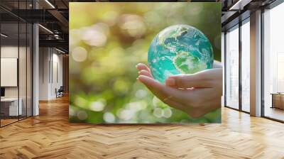 woman hand holding blue green earth globe sphere in environmental protection concept with blurred sunlight bokeh green forest plants in background Wall mural