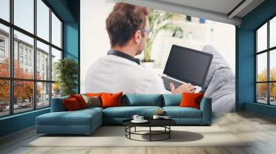 Man listening to music and using laptop in the living room. Wall mural