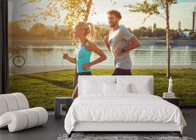 Modern woman and man jogging / exercising in urban surroundings near the river. Wall mural