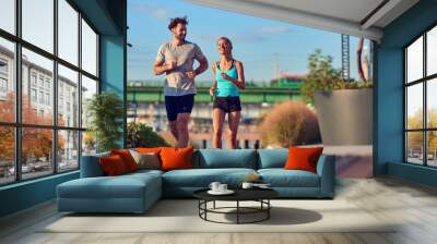 Modern woman and man jogging / exercising in urban surroundings near the river. Wall mural