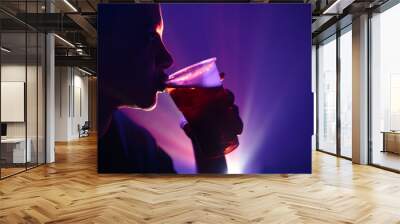 Person holding a plastic cup of beer in the nightclub. Wall mural