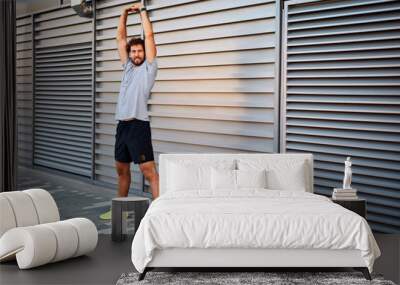 Young man exercising / stretching in urban area. Wall mural