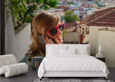 Young woman using cellphone above nice Mediterranean town panorama. Wall mural