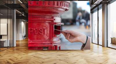 throwing a letter in a red british post box Wall mural