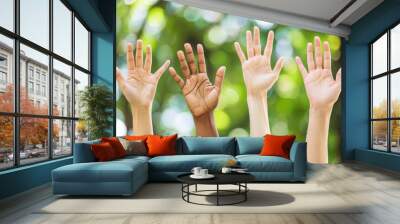 A group of people are holding up their hands in a circle. The hands are of different colors, including black, white, and brown. Concept of unity and togetherness Wall mural