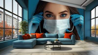 A woman wearing a blue glove is putting on a white surgical mask. Concept of caution and responsibility, as the woman is taking necessary precautions to protect herself and others from potential harm Wall mural